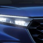 A close up shows the passenger side headlight on a blue 2024 Honda CR-V Sport Touring Hybrid.