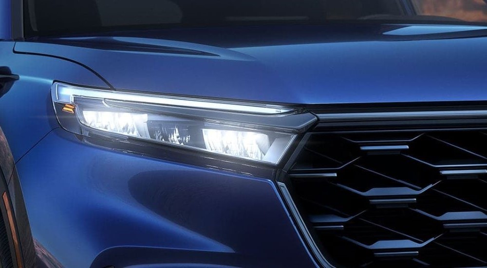 A close up shows the passenger side headlight on a blue 2024 Honda CR-V Sport Touring Hybrid.