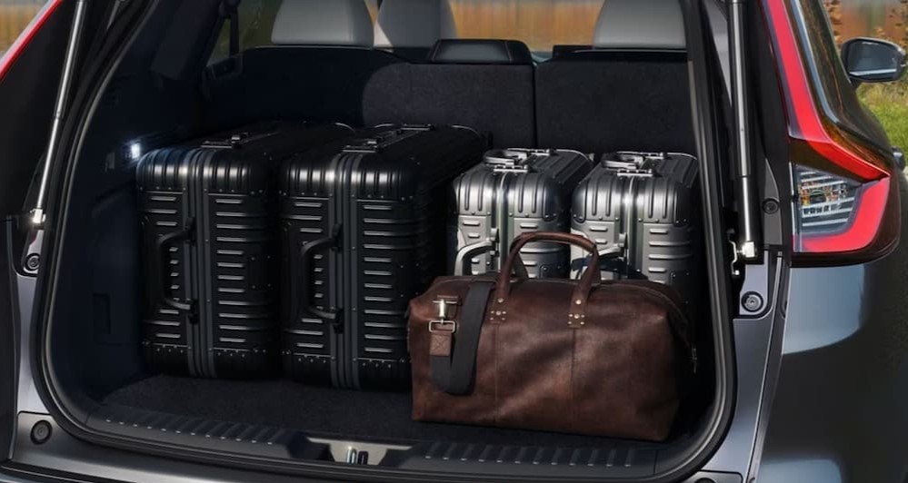 Suitcases are shown in the cargo area of a 2024 Honda CR-V Sport Touring Hybrid.