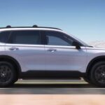 A white 2023 Honda CR-V Sport Touring Hybrid is shown driving on a highway.