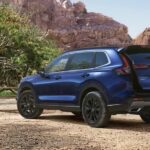 A blue 2024 Honda CR-V Sport Touring Hybrid is shown parked near a picnic table.