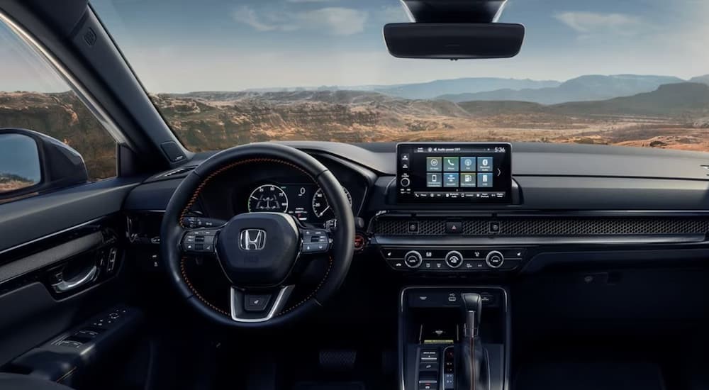 The black interior and dash of a 2024 Honda CR-V Sport Touring Hybrid is shown.