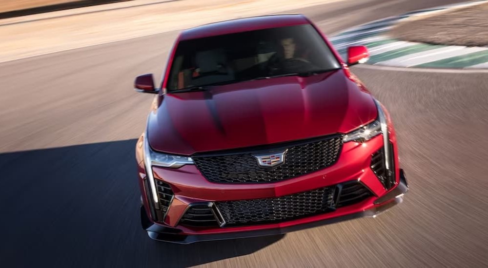 A red 2023 Cadillac CT4 V-Blackwing is shown driving on a racetrack.