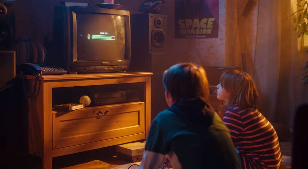 Two children are shown playing video games at home.