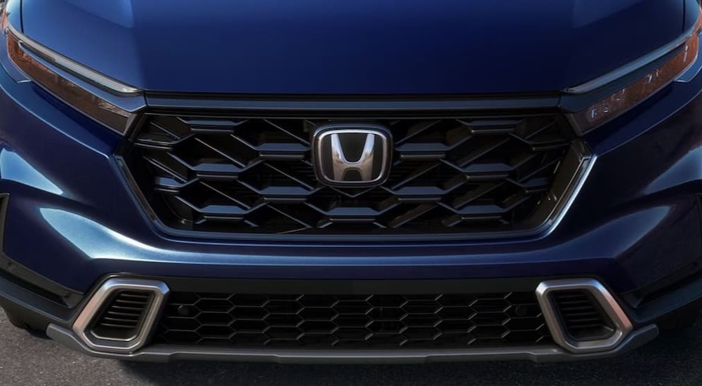 The grille and badge of a blue 2024 Honda CR-V is shown.