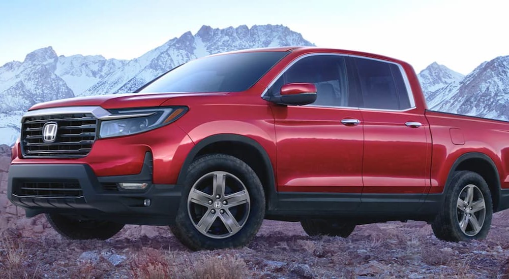 A red 2023 Honda Ridgeline is shown parked near a mountain.