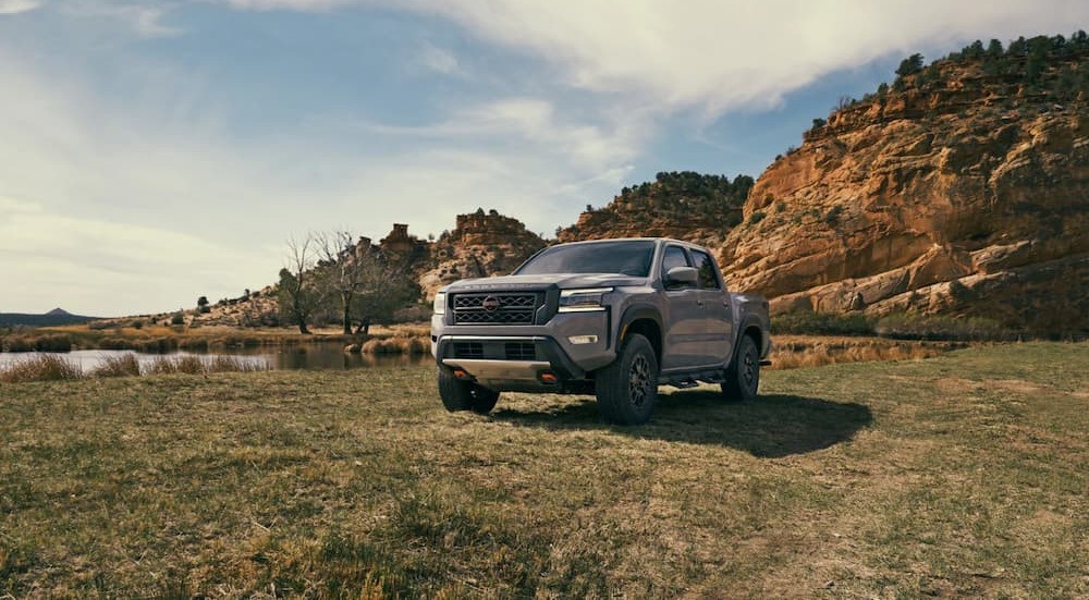 A silver 2023 Nissan Frontier is shown parked on grass.