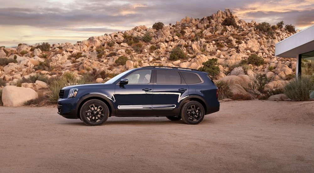 A popular Kia Telluride for sale, a blue 2024 Kia Telluride, is shown parked on sand.