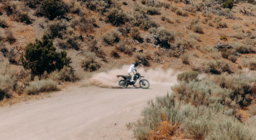 A person is shown from a distance driving around a desert road on a black 2023 Zero FX.