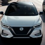 A white 2023 Nissan Sentra is shown from the front during a 2023 Nissan Sentra vs 2023 Toyota Corolla comparison.