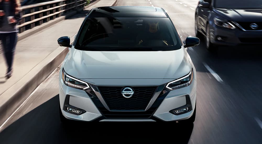A white 2023 Nissan Sentra is shown from the front during a 2023 Nissan Sentra vs 2023 Toyota Corolla comparison.
