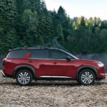 A popular Nissan Pathfinder for sale, a red 2023 Nissan Pathfinder, is shown parked near a lake.