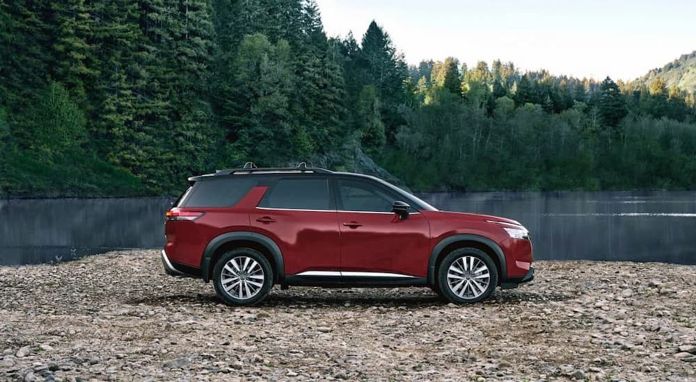 A popular Nissan Pathfinder for sale, a red 2023 Nissan Pathfinder, is shown parked near a lake.