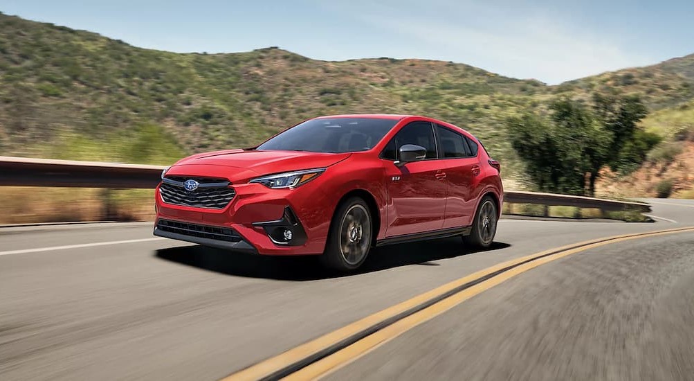 A red 2024 Subaru Impreza RS is shown driving on a highway after visiting a car dealership.