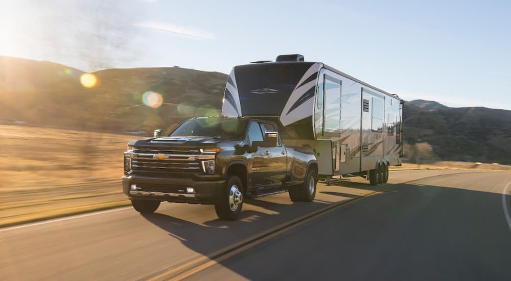 A black 2021 Chevy Silverado 3500 is shown towing a trailer.