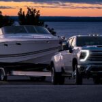 A popular heavy duty trucks for sale, a 2024 Chevy Silverado 2500 HD, is shown towing a boat.