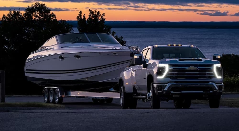 A popular heavy duty trucks for sale, a 2024 Chevy Silverado 2500 HD, is shown towing a boat.