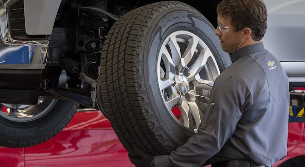 A mechanic is shown putting a large tire on a Chevy vehicle.