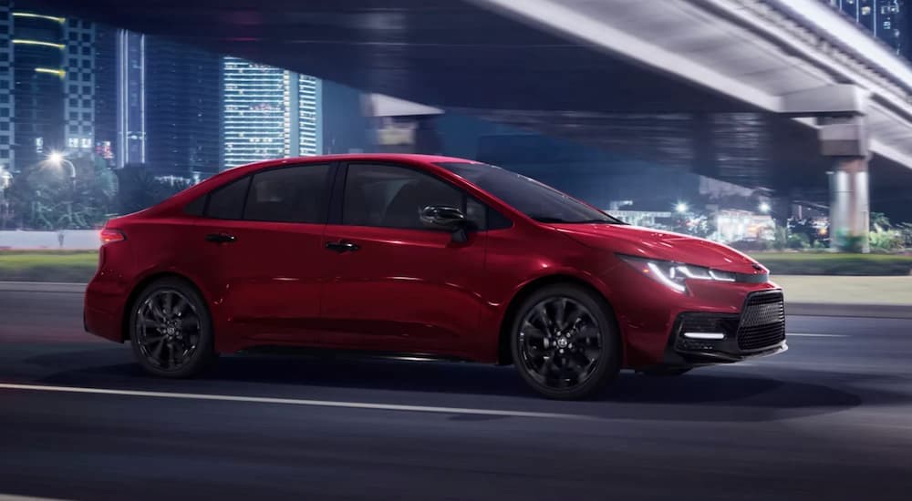 A red 2022 Toyota Corolla SE is shown driving under an overpass from a used Toyota dealer..