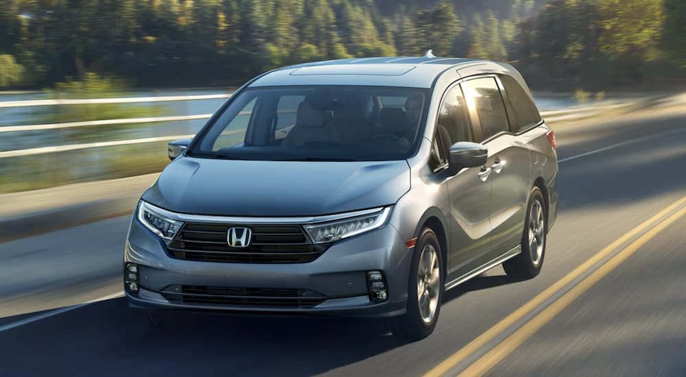 A silver 2023 Honda Odyssey Elite is shown driving on a highway.