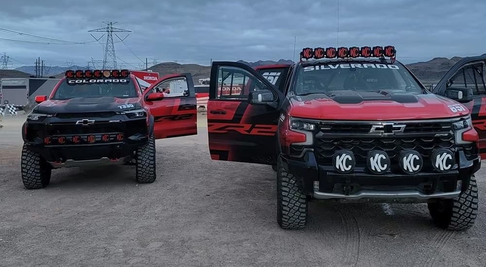 A red 2023 Chevy Colorado ZR2 and a red 2023 Silverado ZR2 are shown parked next to one another.