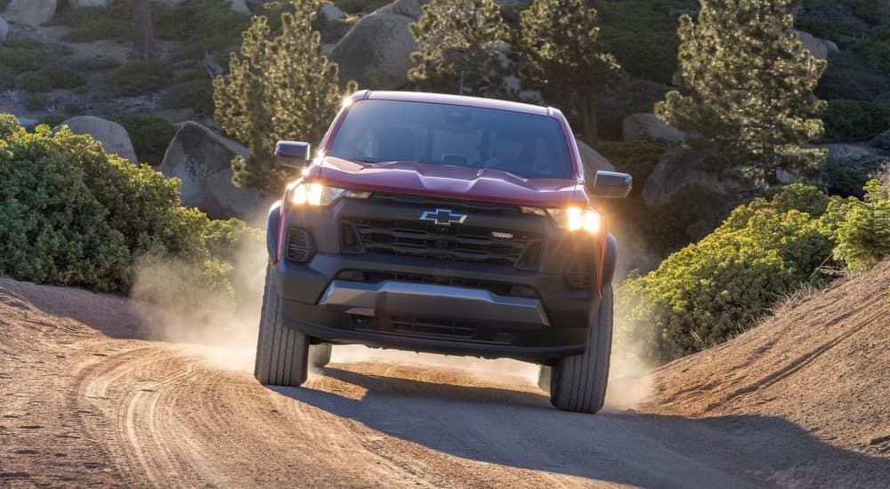 A red 2023 Chevy Colorado Trail Boss is shown driving.