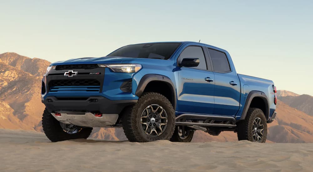 A blue 2023 Chevy Colorado ZR2 is shown driving off-road in a desert.
