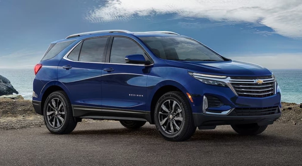 A blue 2023 Chevy Equinox LS is shown parked near an ocean.