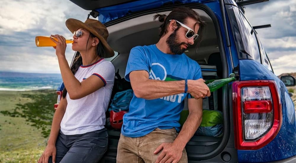 Two people are shown drinking beverages near a blue 2023 Ford Bronco Sport Big Bend.