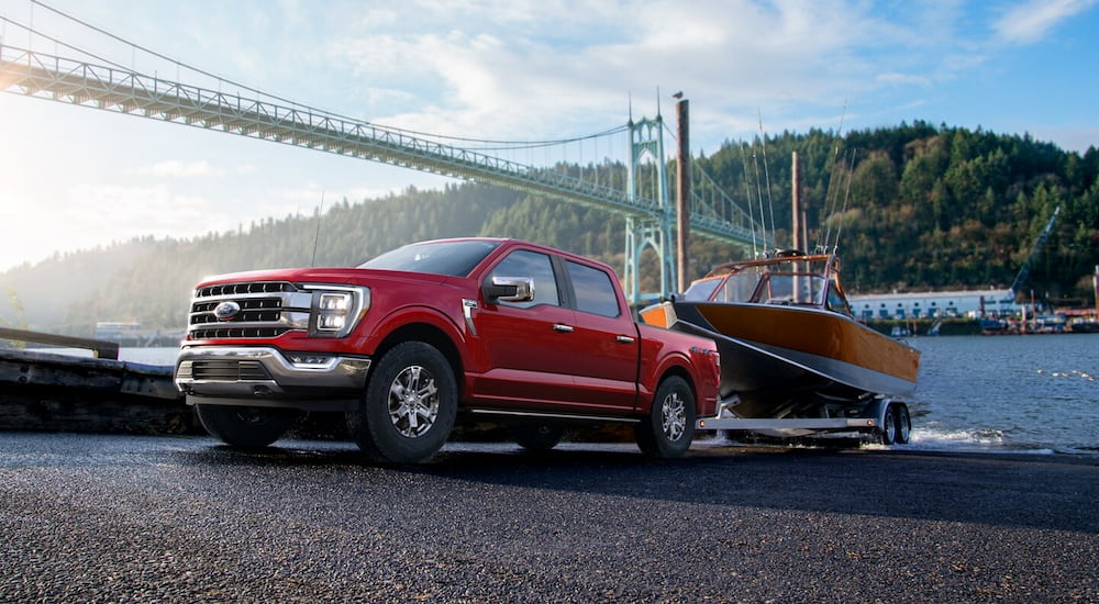 A red 2023 Ford F-150 XLT is shown towing a boat out of a body of water.