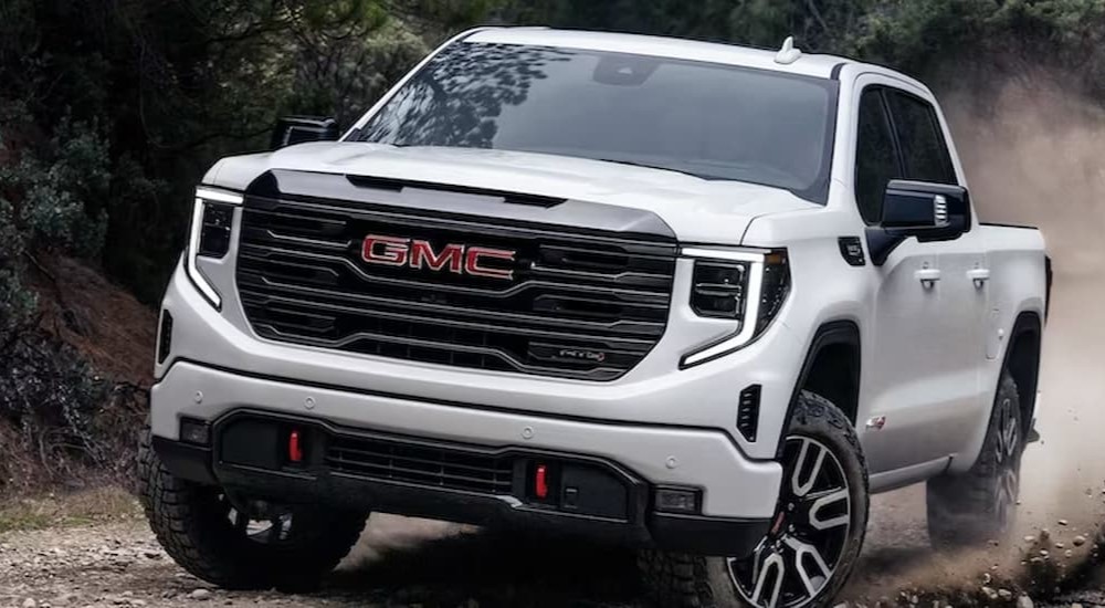 A white 2023 GMC Sierra 1500 AT4X is shown driving off-road after viewing a GMC Sierra 1500 for sale.