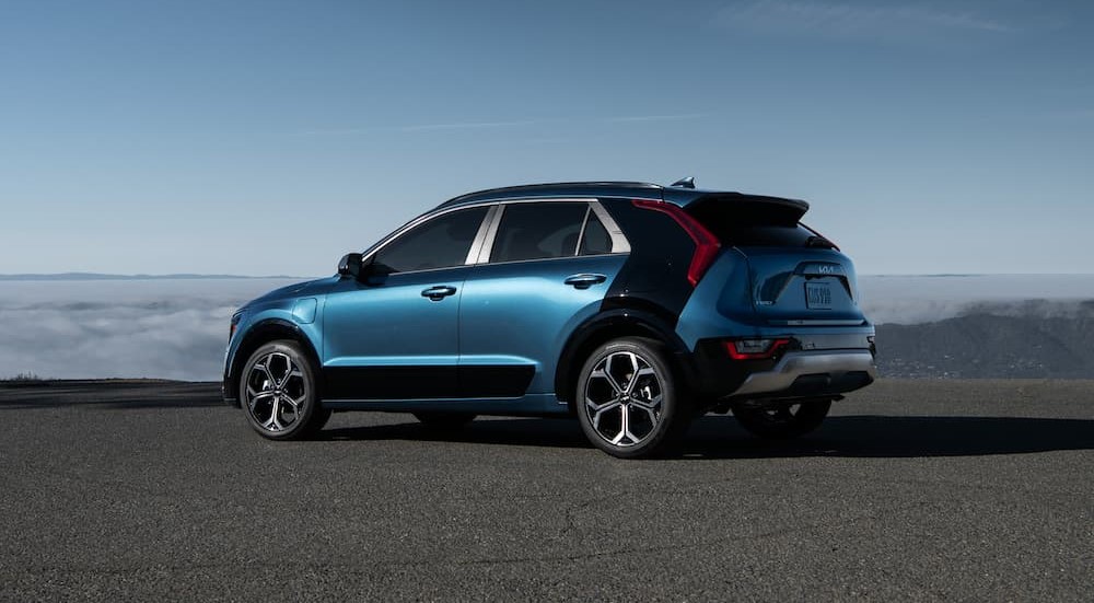 A blue and black 2023 Kia Niro Plug-in Hybrid is shown parked under a blue sky.