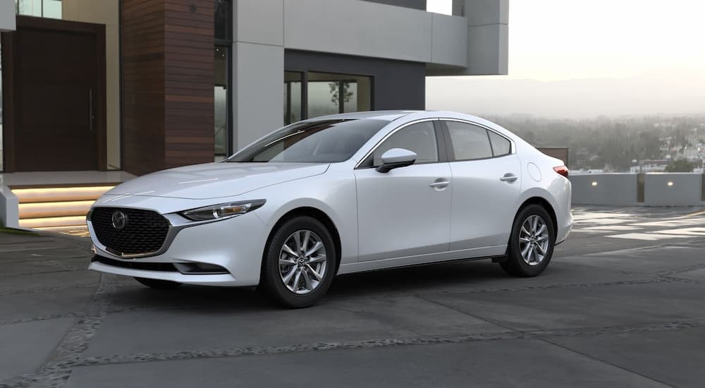 A white 2023 Mazda 3 is shown parked near a house.