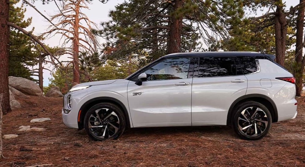 A white 2023 Mitsubishi Outlander PHEV is shown parked off-road.