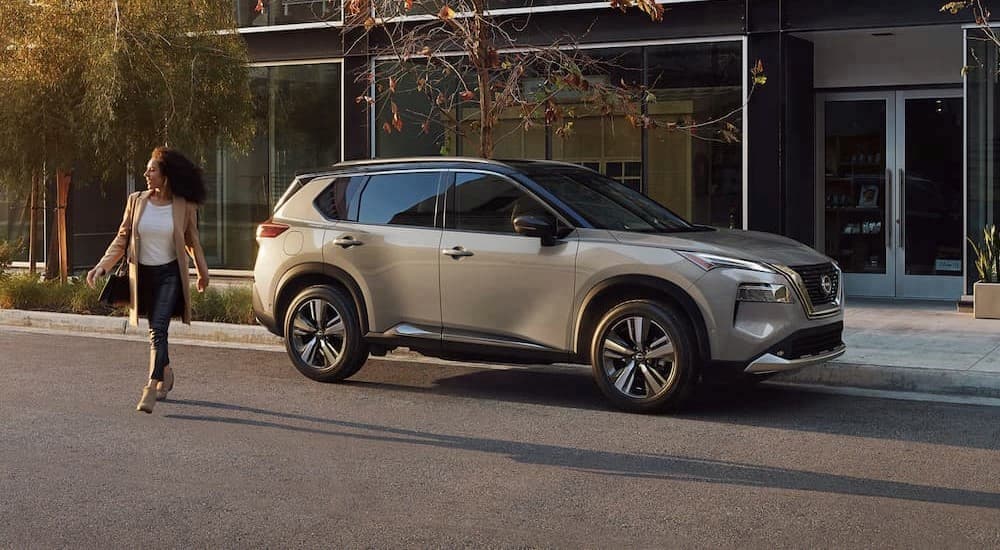 A silver 2023 Nissan Rogue Platinum is shown parked on a city street after competing in a 2023 Nissan Rogue vs 2023 Buick Envision comparison.