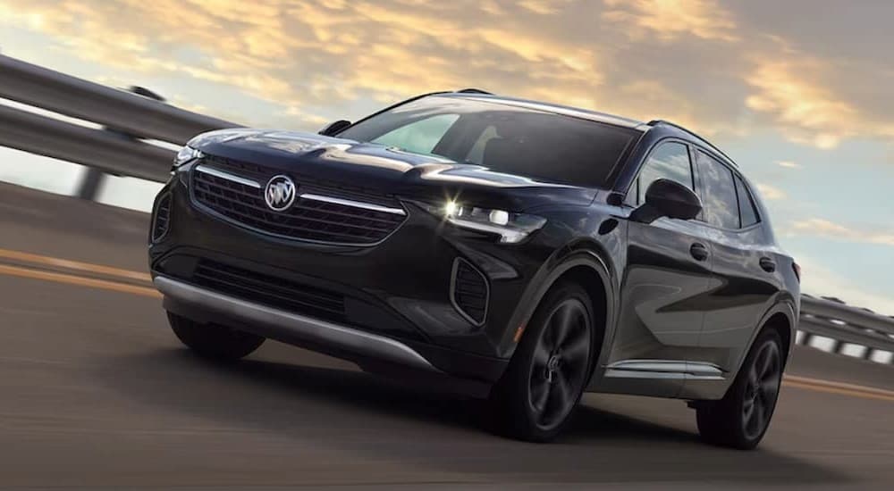 A dark blue 2023 Buick Envision is shown driving on a highway.