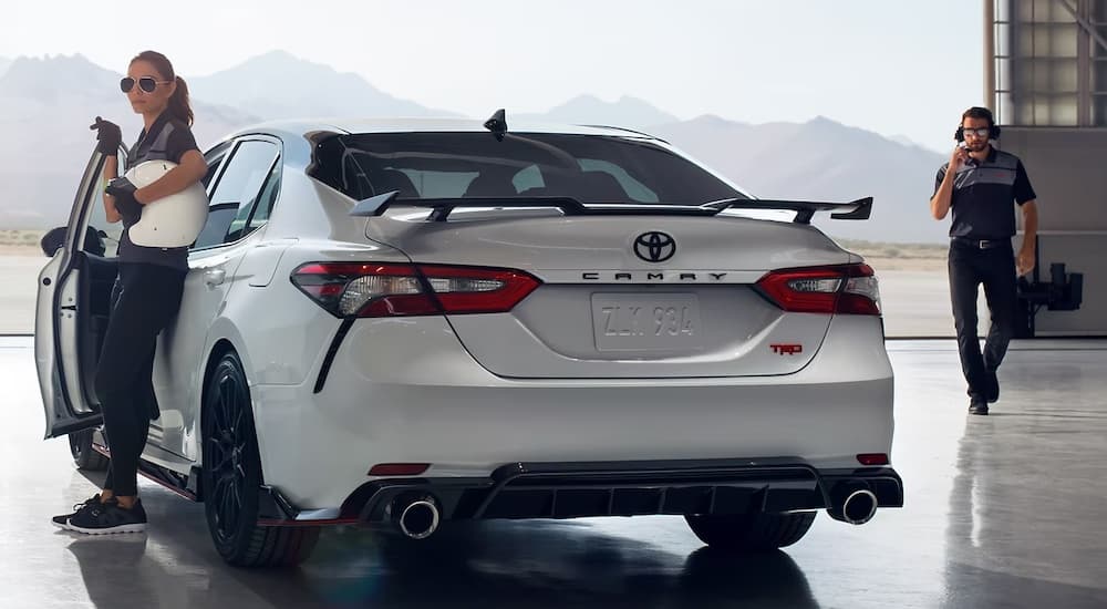 A person is shown exiting a white 2023 Toyota Camry TRD.