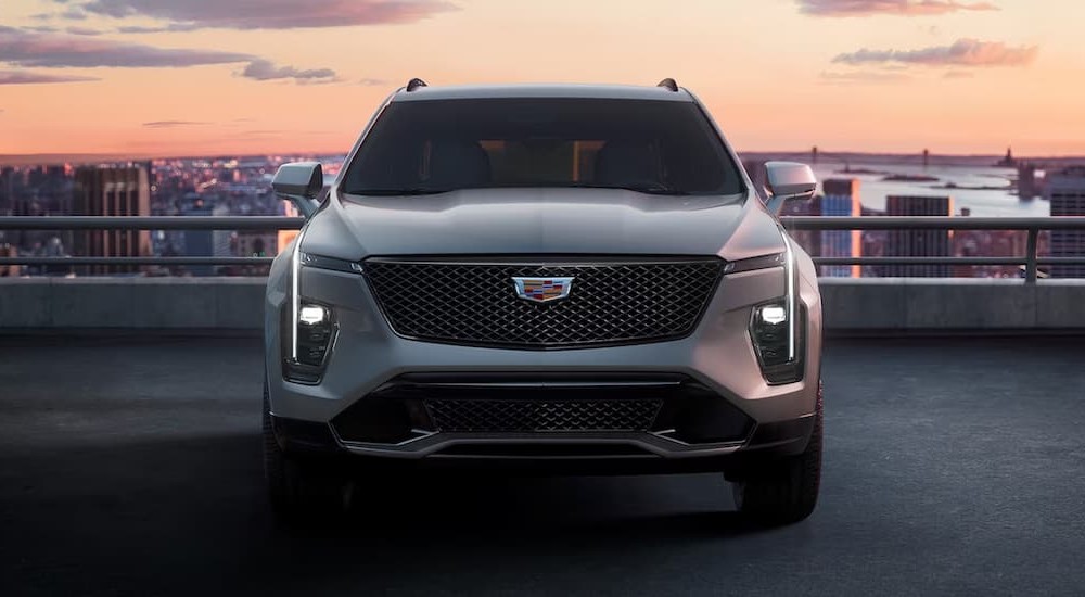 A silver 2024 Cadillac XT4 is shown parked near a city.