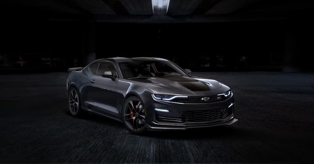 A black 2024 Chevy Camaro is shown parked in a dark garage.