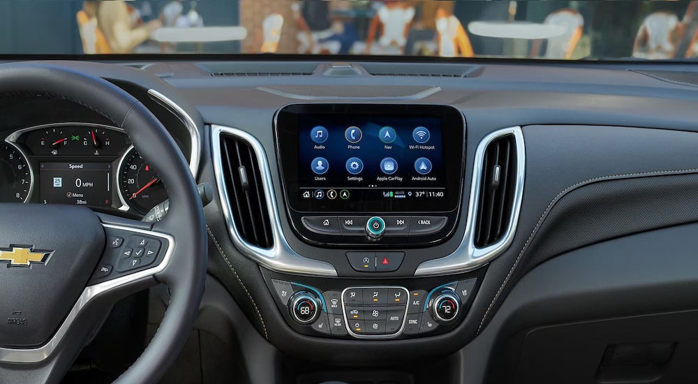 The black interior of a 2024 Chevy Equinox, showing the steering wheel and dashboard screen.