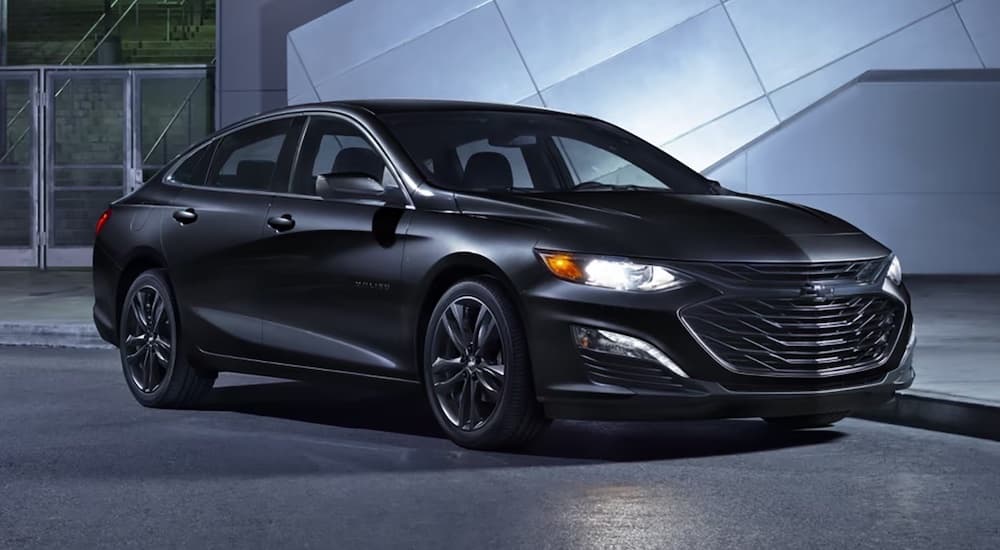 A black 2024 Chevy Malibu Midnight Edition is shown parked on a driveway.