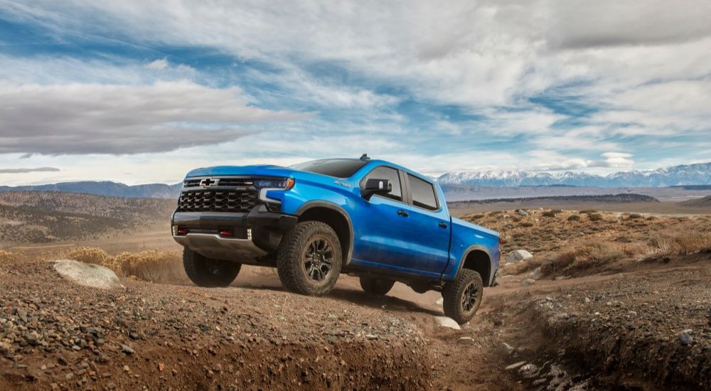 A blue 2024 Chevy Silverado 1500 ZR2 is shown off-road.