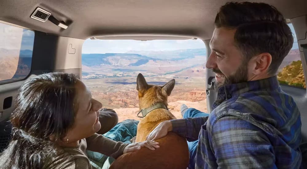 A couple and their dog are shown resting in the hatchback of a 2024 Toyota Land Cruiser.
