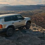 A silver 2024 Toyota Land Cruiser is shown parked on a cliff.