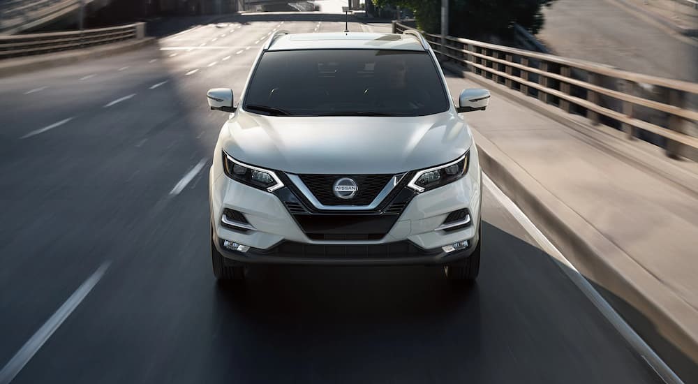 A white 2022 Nissan Rogue Sport is shown driving on a bridge.