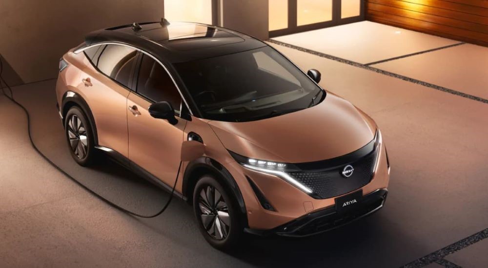 A popular electric vehicle for sale, an orange 2023 Nissan Ariya, is shown charging.