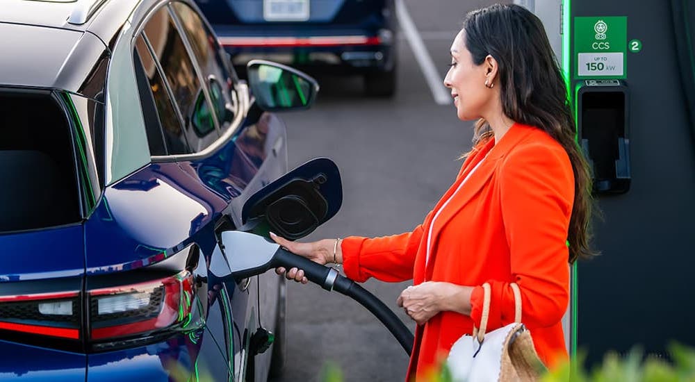 A person is shown charging a blue 2023 Volkswagen ID.4.