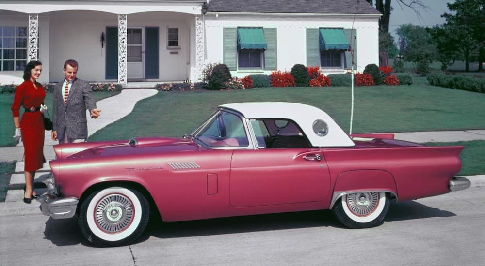 A red and white 1957 Ford Thunderbird is shown parked on a neighborhood street.