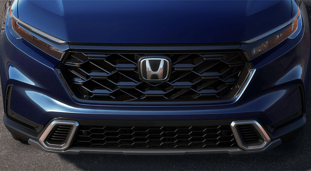 A close up of the grille and headlights on a dark blue 2023 Honda CR-V Hybrid is shown.