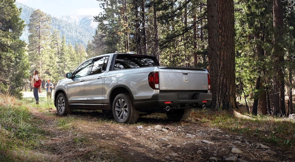 A white 2021 Honda Ridgeline is shown from the rear at an angle in the forest after leaving a used Honda dealer.